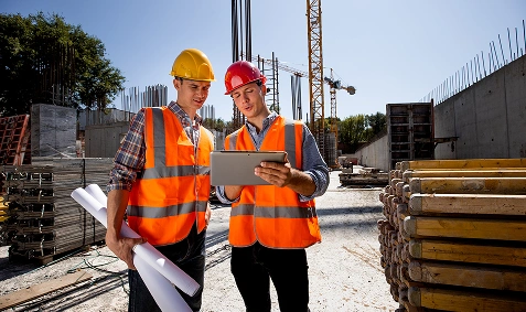 Two AppMatic Tech field engineers reviewing project data on a tablet at a construction site