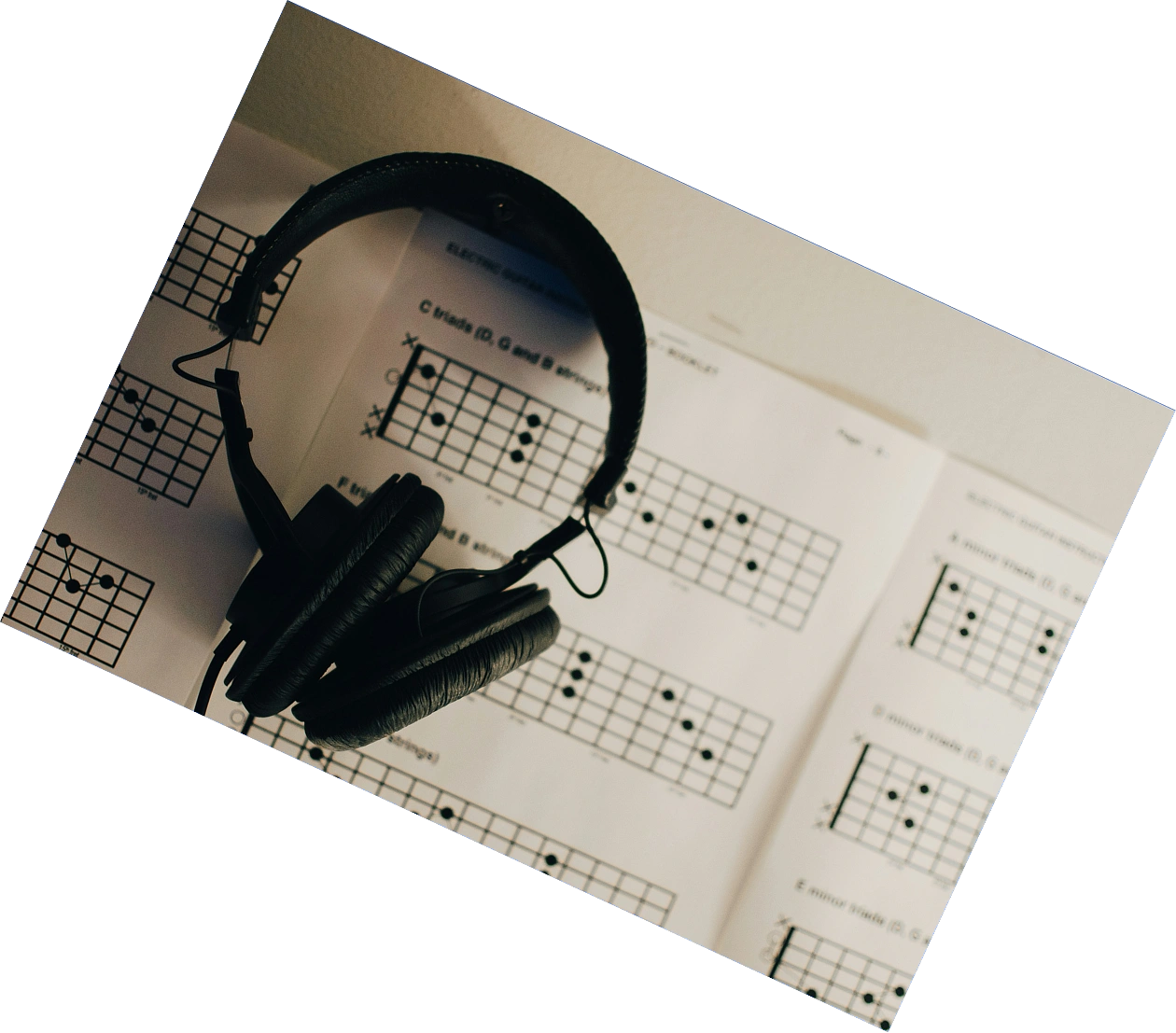 Headphones resting on a printed guitar chord book, part of the listening app AppMatic Tech builds