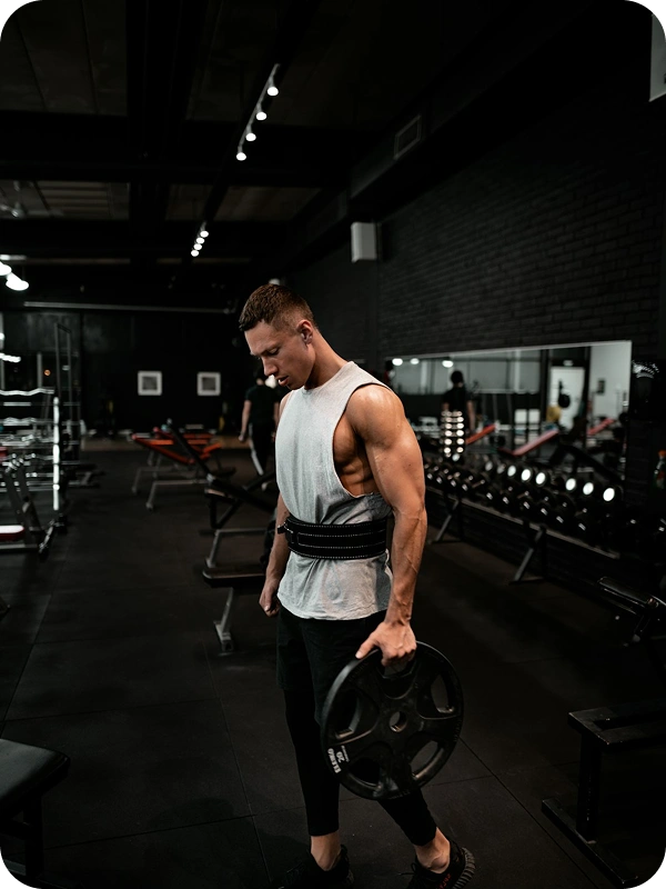 Athlete carrying a weight plate across a gym floor, representing the strength and training products AppMatic Tech builds software for